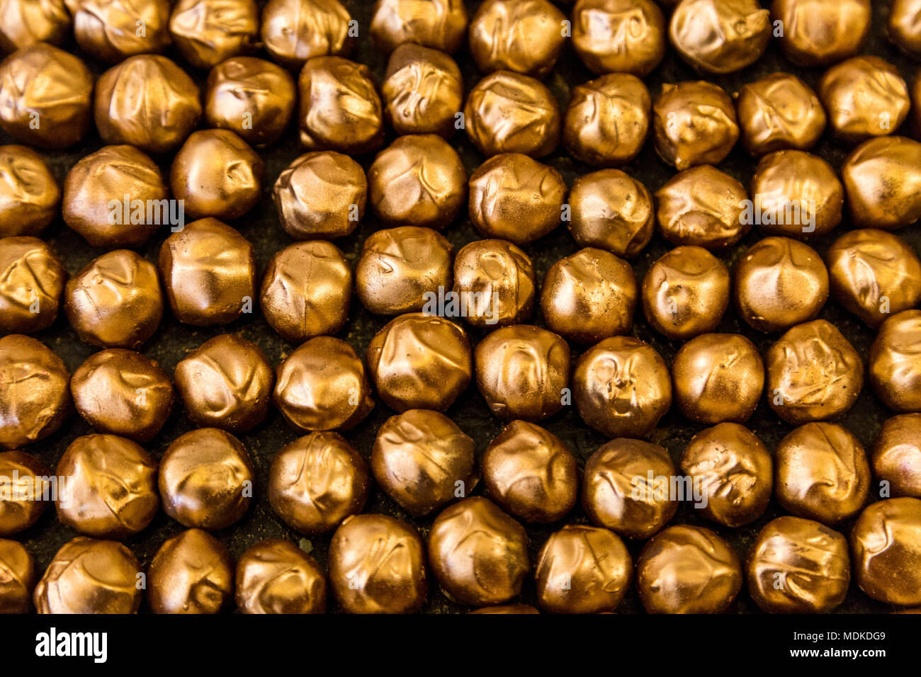Rangées de pralines en chocolat revêtement doré (fond Cacao Sucres Dark House, Londres, UK) Banque D'Images