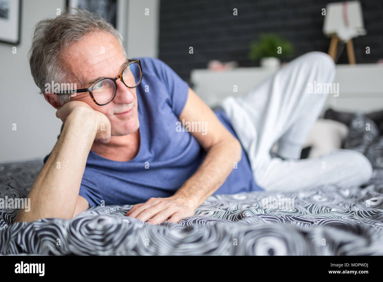 Portrait of senior man lying on bed penser Banque D'Images