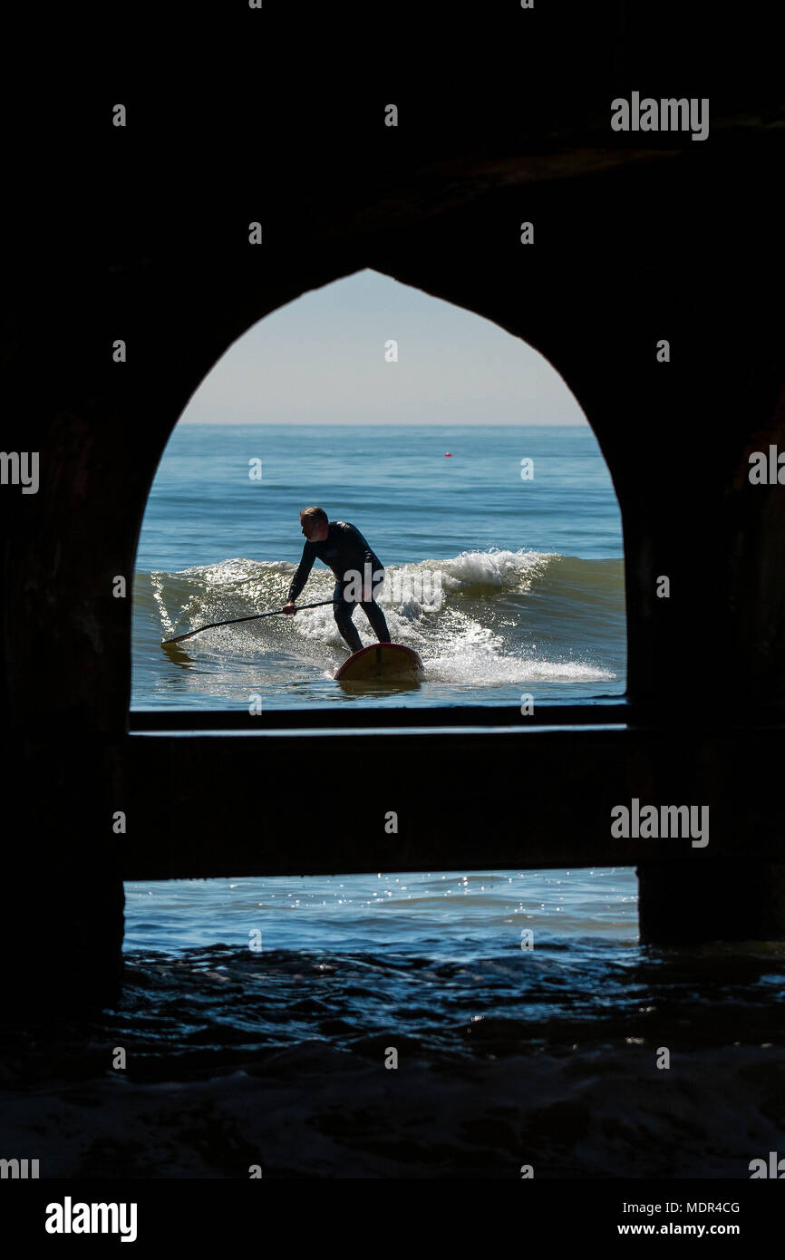 19.04.18. Météo de Bournemouth. Une pagaie boarder surfe sur une vague à côté de la jetée de Bournemouth car les températures montent sur la côte sud du Royaume-Uni. Banque D'Images