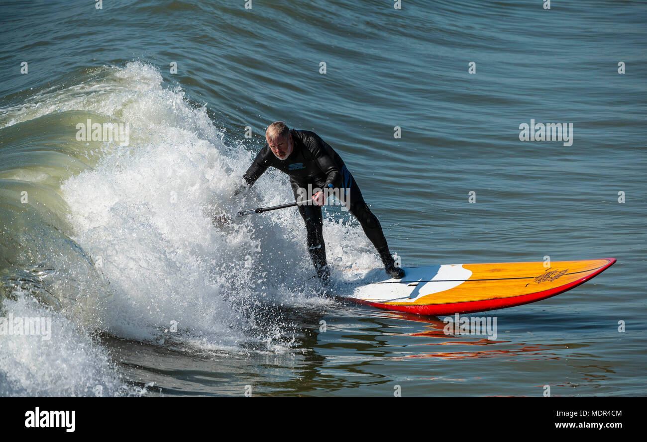 19.04.18. Météo de Bournemouth. Une pagaie boarder surfe sur une vague à côté de la jetée de Bournemouth car les températures montent sur la côte sud du Royaume-Uni. Banque D'Images