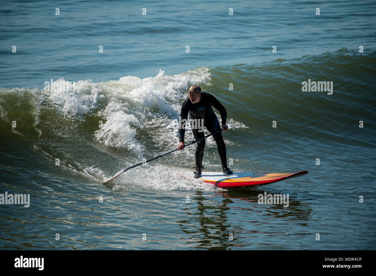 19.04.18. Météo de Bournemouth. Une pagaie boarder surfe sur une vague à côté de la jetée de Bournemouth car les températures montent sur la côte sud du Royaume-Uni. Banque D'Images