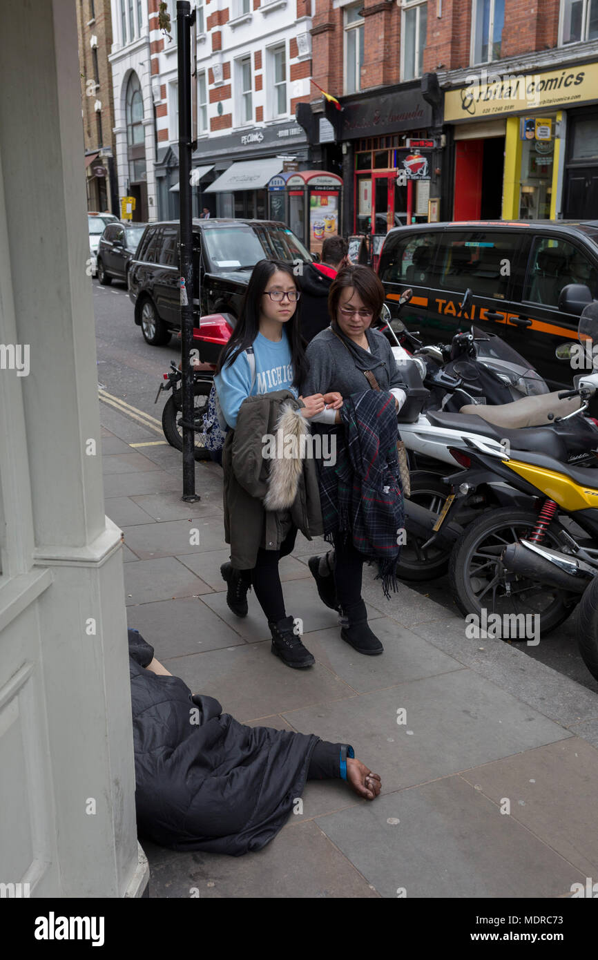 Les passants passent devant un sans-abri dont la main est sur le trottoir en grand Newport Street, le 16 avril 2018, à Londres, en Angleterre. Banque D'Images