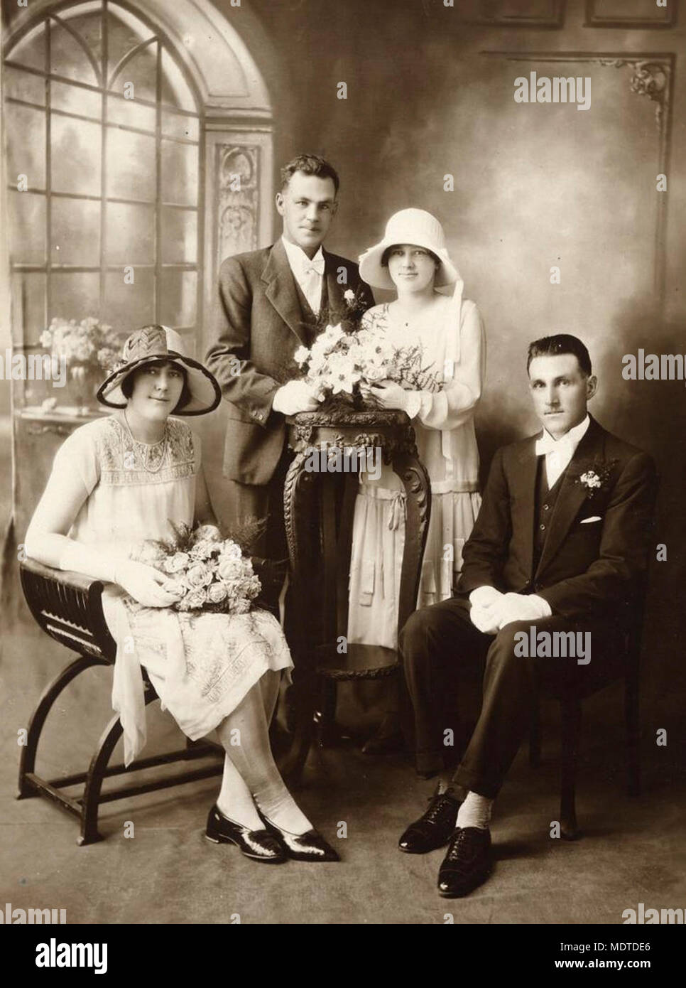 Fête de mariage, le nord du Queensland, 1920-1930. Studio photo d'une jeune mariée et le jeune marié avec leur meilleur homme et de demoiselle. La mariée et le marié sont posés derrière un stand en bois sculpté, le bouquet de mariée sur le support. Le meilleur homme et de demoiselle sont assis à l'avant et de chaque côté des mariés. La mariée de demoiselle et porter des robes de style typique de la vingtaine et chapeaux Banque D'Images