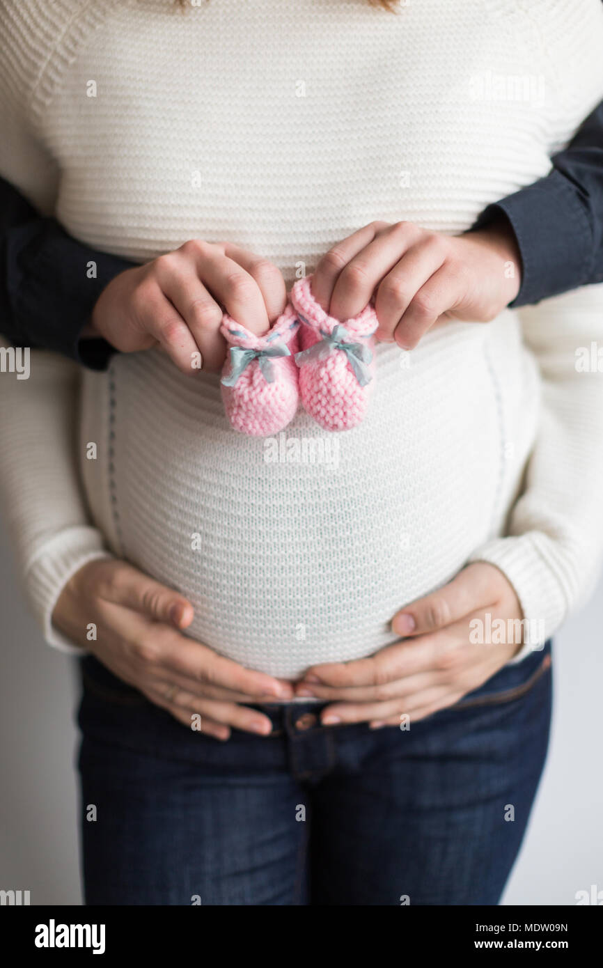 Mode bébé, amour, la grossesse concept. Il y a près de femmes et d'hommes  en armes, jeune mère tient ses mains sur son ventre et son mari est  maintenant un couple de