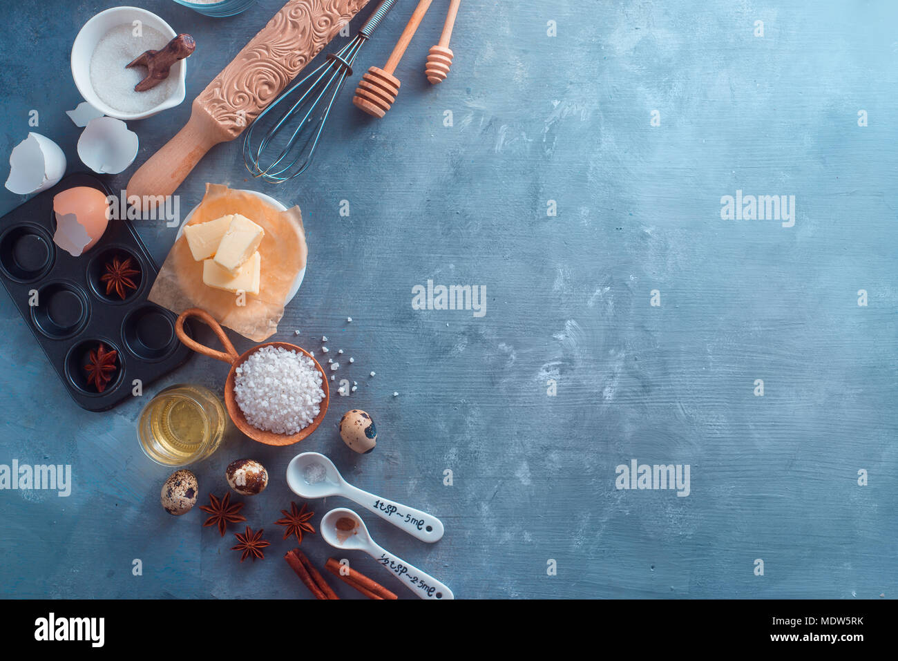 Concept de cuisson avec outils de cuisson et les ingrédients. Rouleau à pâtisserie, cuillères de miel, muffin tin, mélanger au fouet, la farine, le beurre sur un fond en béton, en-tête avec copie espace Banque D'Images