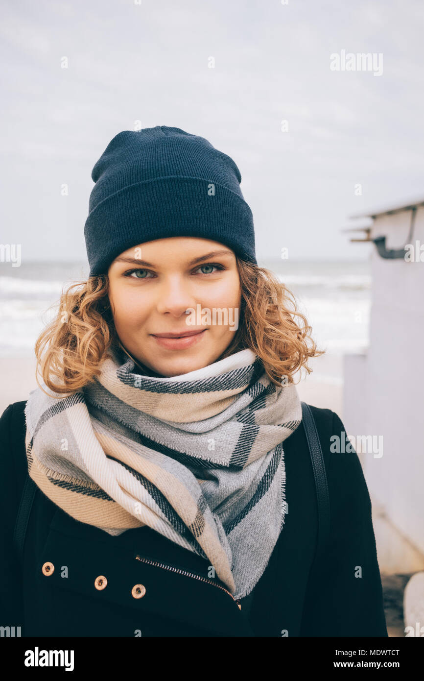 Portrait de jeune femme aux cheveux bouclés portant manteau, écharpe et  Beanie Hat dans la saison froide. Hipster girl smiling standing sur le fond  de l'hiver s Photo Stock - Alamy