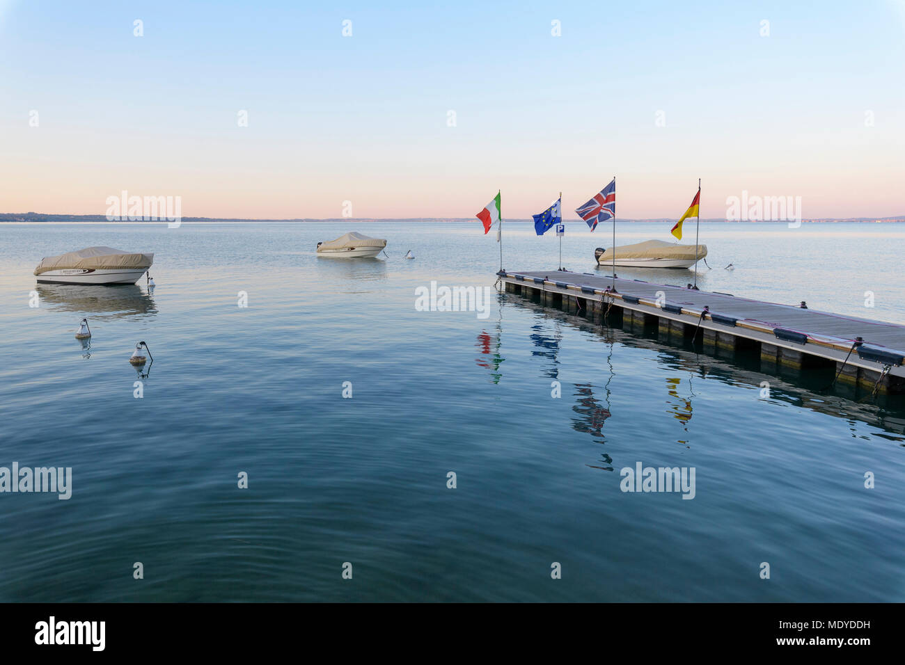 Couverts, bateaux amarrés à la jetée à l'aube sur le lac de Garde (Lago di Garda) à Bardolino en Vénétie, Italie Banque D'Images