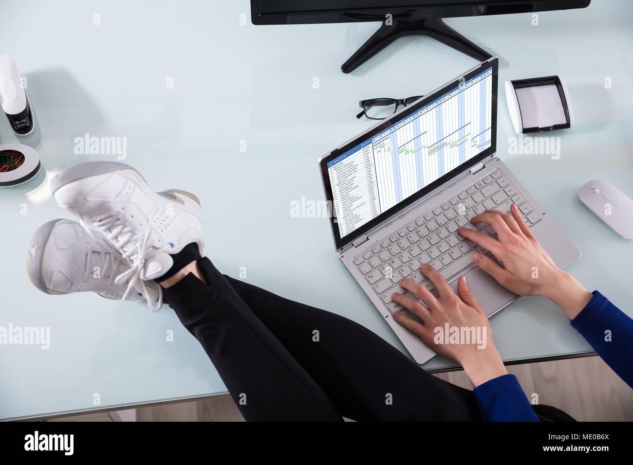La main d'affaires travaillant sur ordinateur portable avec l'aide du diagramme de Gantt jambes croisées sur Office 24 Banque D'Images