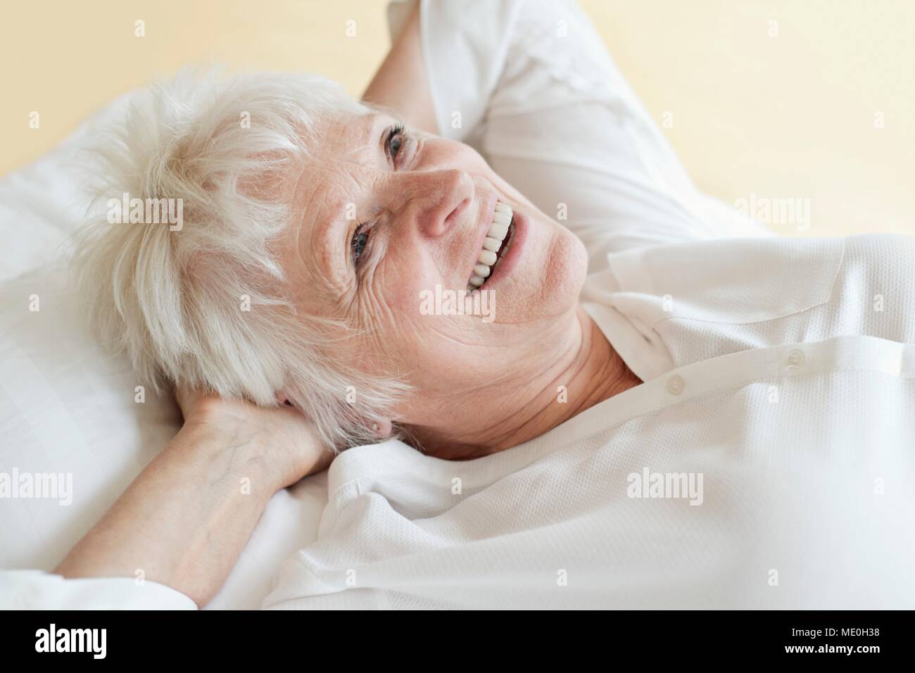 Senior woman lying down avec les mains derrière la tête. Banque D'Images