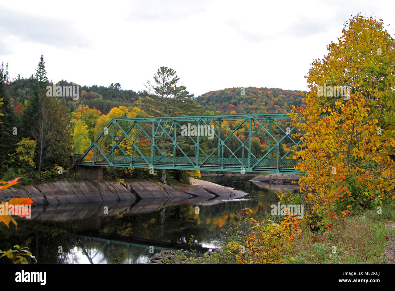 Vue panoramique de l'automne de rivière paisible, pont et arbres aux couleurs automnales Banque D'Images