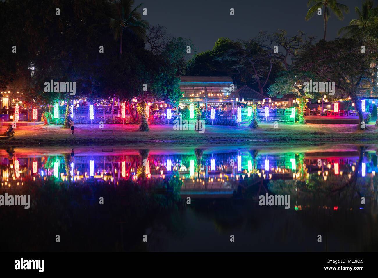 CHIANG MAI THAILAND - janvier 29, 2018 ; des gens dans les restaurants de rivières Ping riverside lumineux bordé d'arbres derrière Banque D'Images