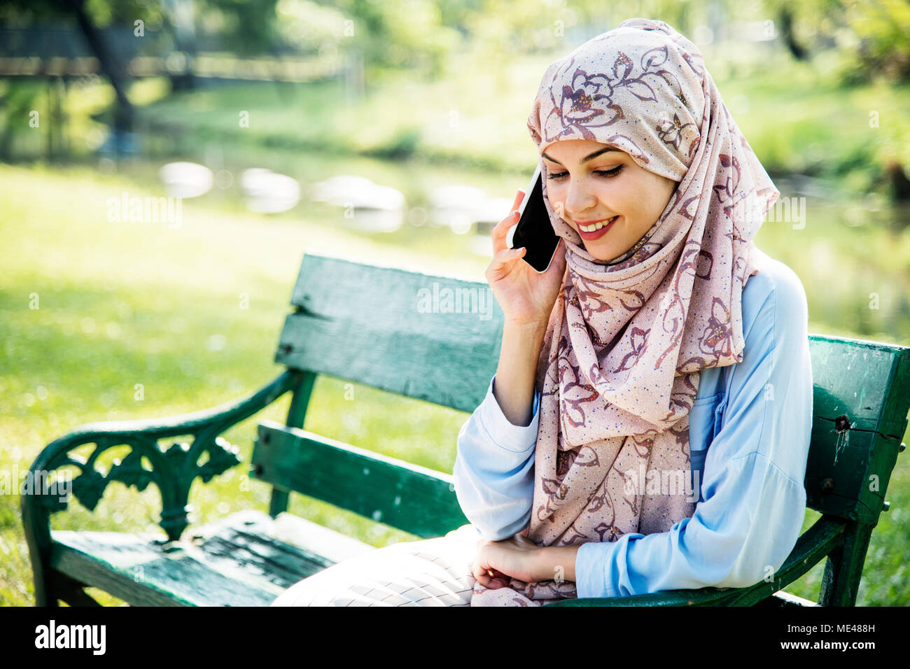Femme musulmane à l'aide de téléphone mobile avec smiling at park Banque D'Images