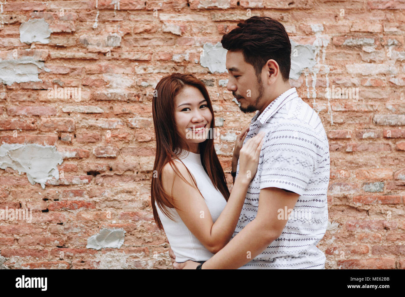 Joli couple asiatique par un mur de briques Banque D'Images