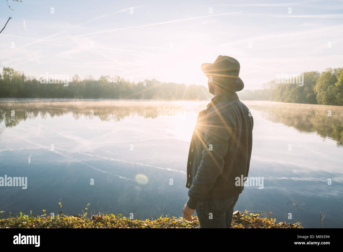Jeune homme en contemplant la nature par le lac au lever du soleil, le printemps, la France, l'Europe. Les gens voyagent de détente dans la nature concept. Image tonique Banque D'Images