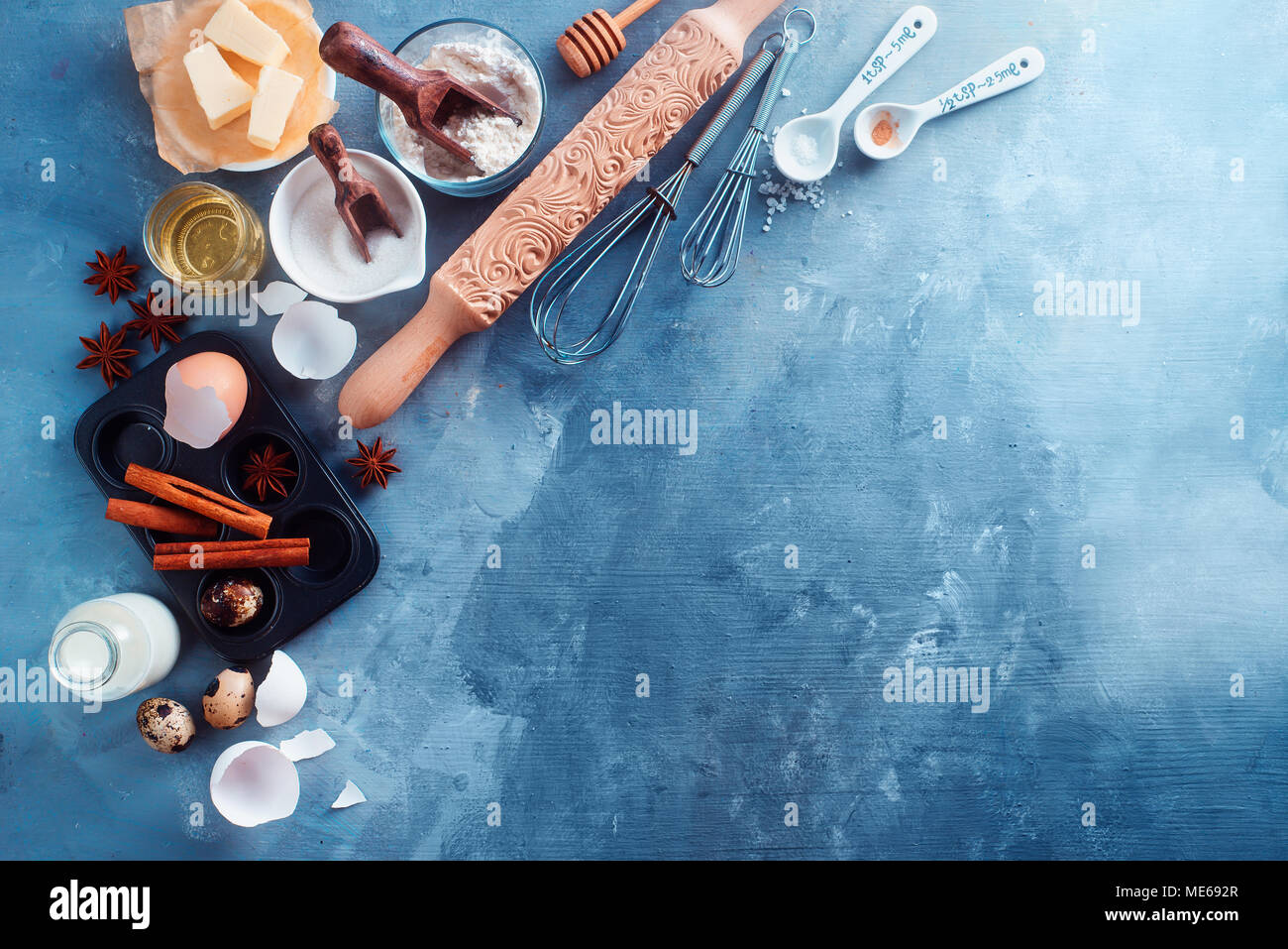 Ingrédients et outils de mise à plat. Rolling pin sculpté, muffin étain, Flor de beurre, le sucre et les épices sur une table de cuisine en béton bleu with copy space Banque D'Images