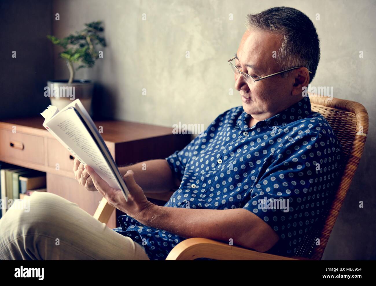Senior man reading book at home Banque D'Images