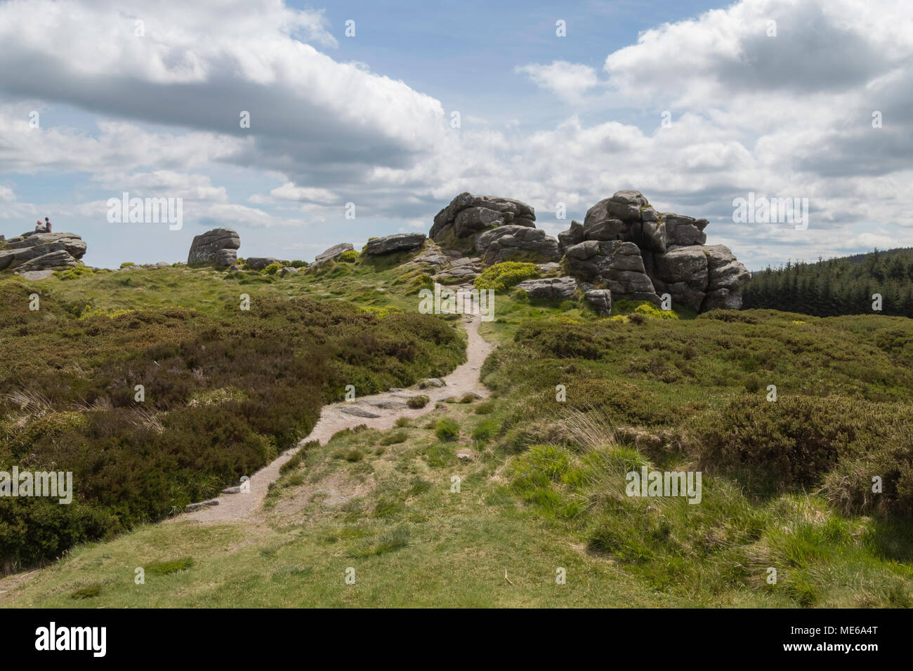 Sentier étroit menant au sommet de la colline, de gros rochers s au sommet, sous un ciel bleu avec des nuages blancs épais Banque D'Images