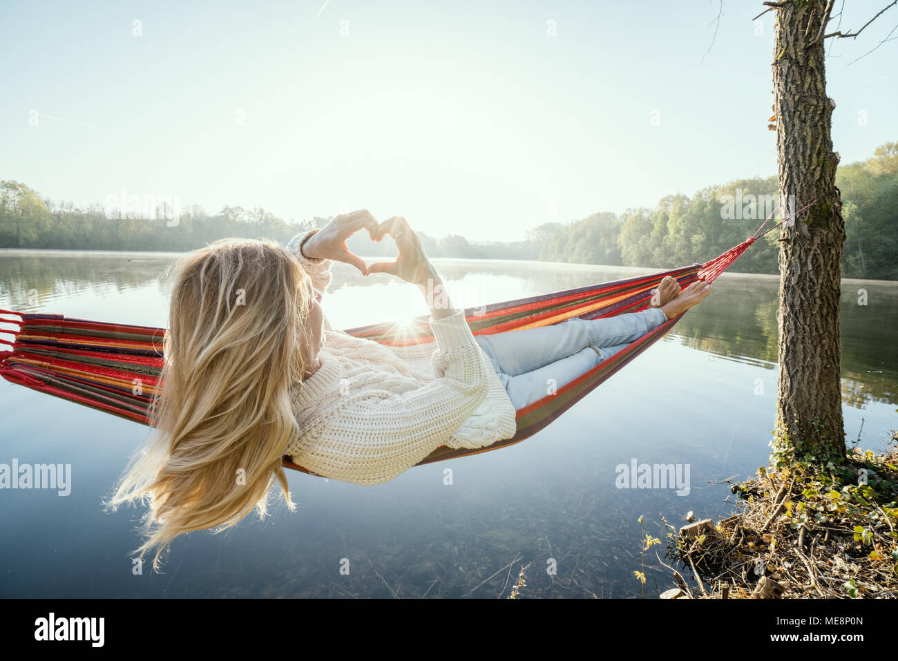 Young woman relaxing on hammock de prendre une forme de coeur sur le magnifique lac image paysage, aimer les gens romance concept. France, Europe Banque D'Images
