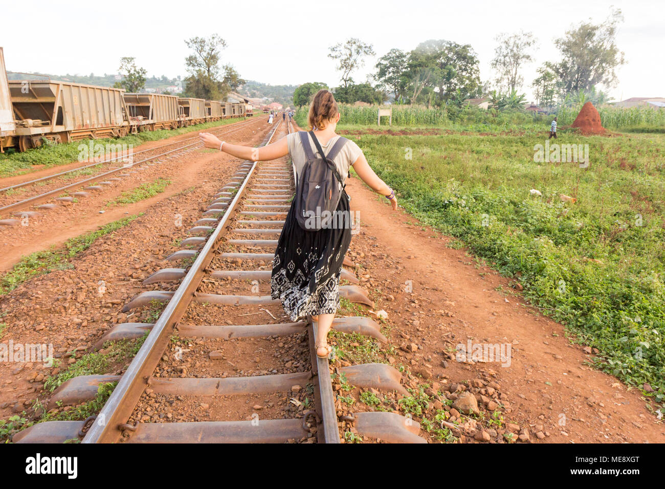 Lugazi, en Ouganda. 17 mai 2017. Une fille à la peau blanche (appelé 'mzungu' ou 'Muzungu' par les habitants) est la marche et en équilibre sur un rail sur une voie de chemin de fer. Banque D'Images