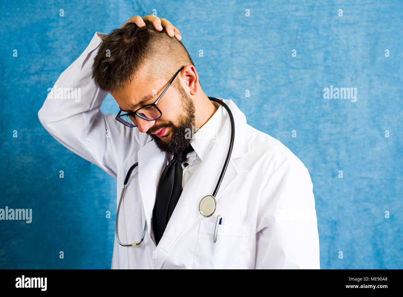 Portrait d'un jeune médecin contre fond bleu Banque D'Images