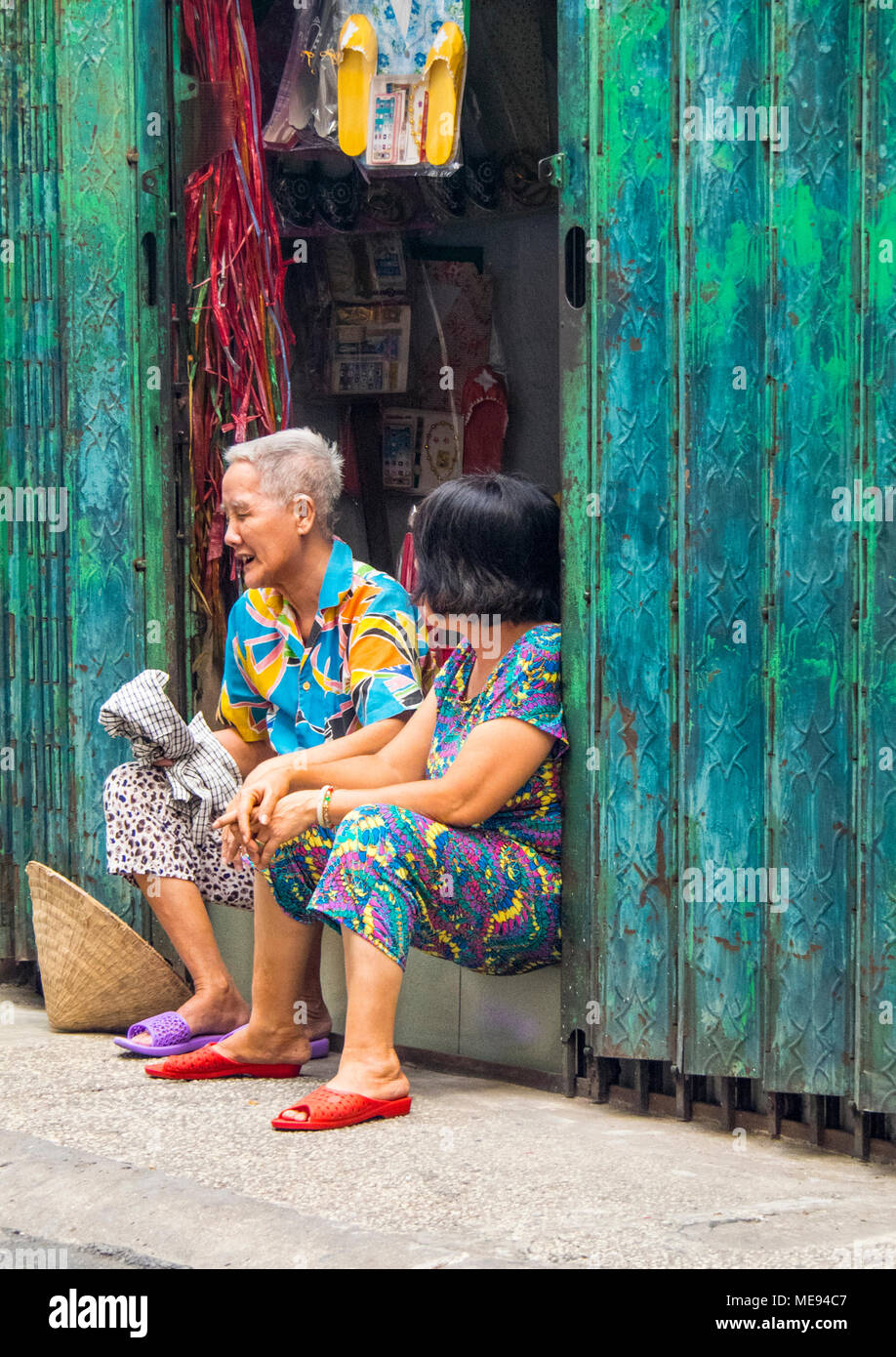 Deux femmes âgées l'un et l'autre moyen-âge assis dans l'embrasure d'avoir une conversation tranquille à Ho Chi Minh City, Vietnam. Banque D'Images