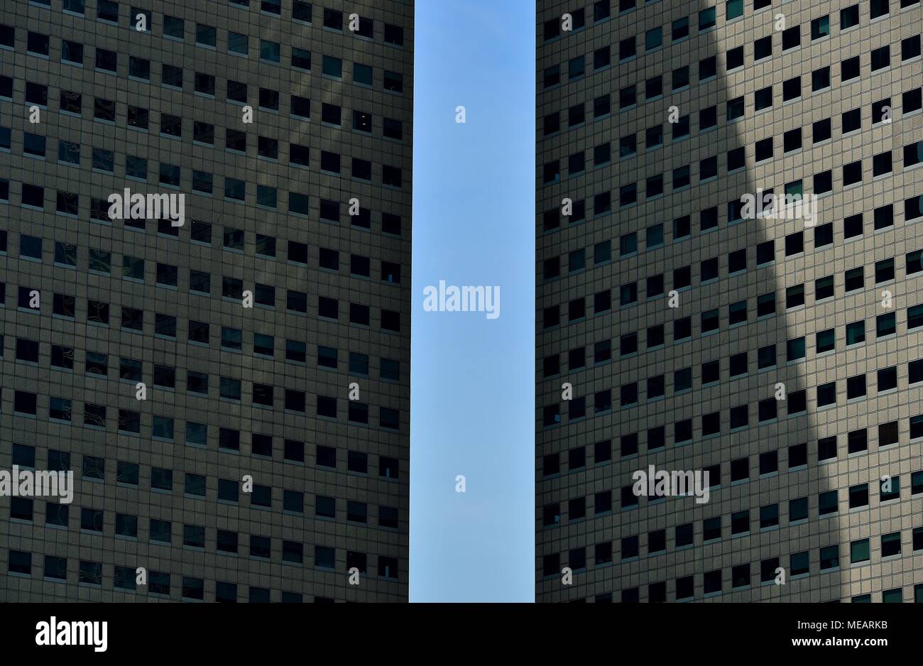Vue de face de deux tours de bureaux moderne de haute élévation encadrant un ciel bleu à Singapour comme motif de fond avec la géométrie et la symétrie forte Banque D'Images