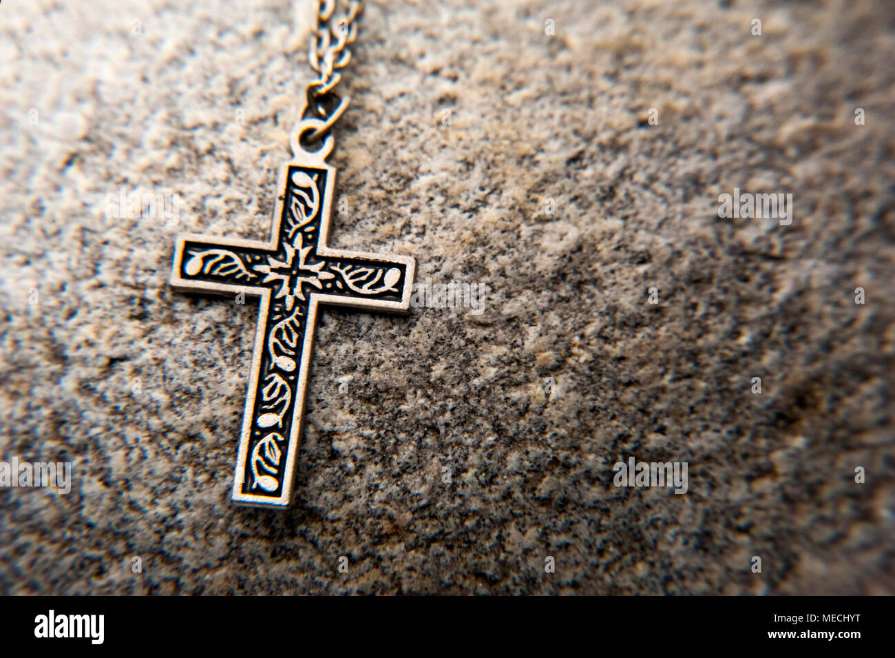 Crucifix sur une chaîne posée sur un rocher Banque D'Images