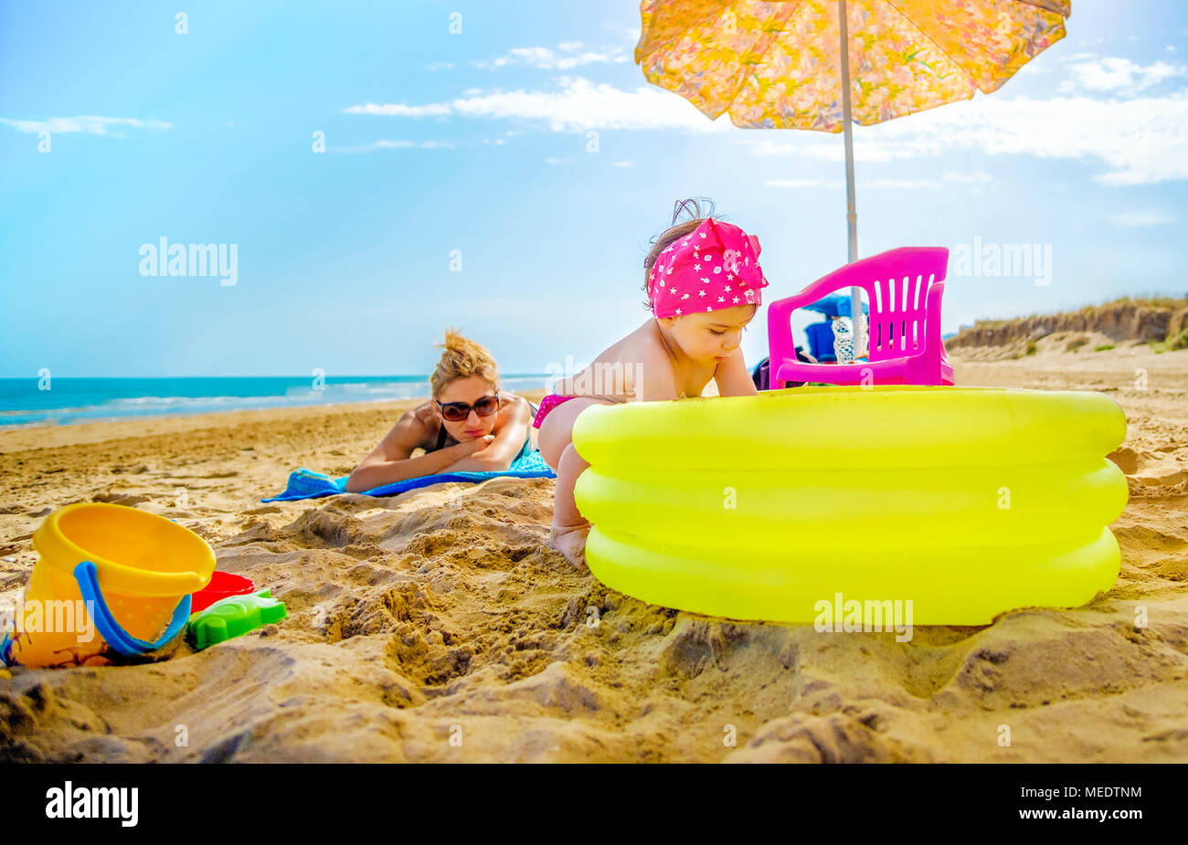 Petite Fille Joue Avec Piscine Gonflable Jaune Sur La Plage Tandis Que La Maman Consulte Ses Tout En Bronzant Sur La Serviette De Plage Photo Stock Alamy