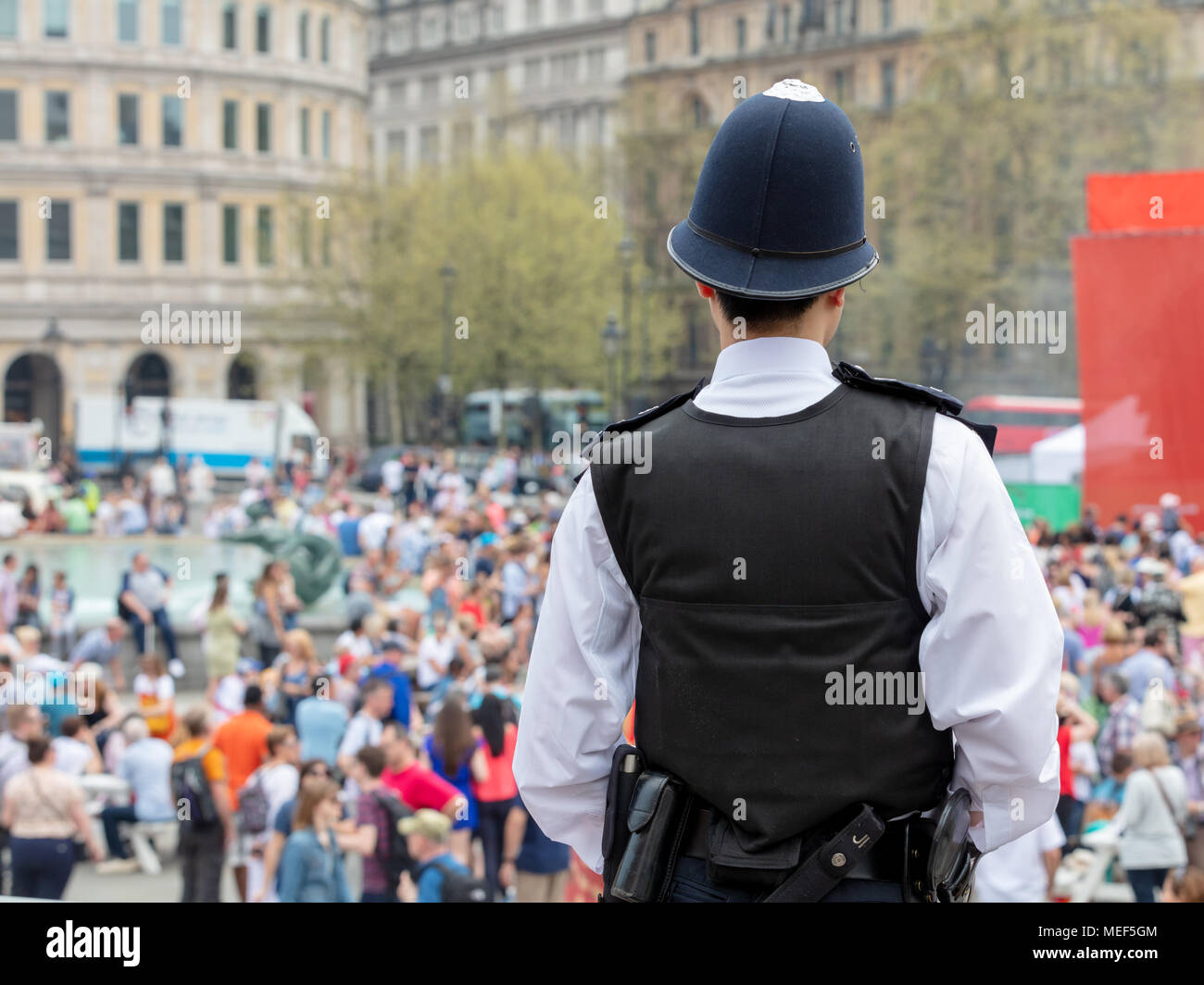 Vue arrière d'un agent de police qui surveille les foules à Trafalgar Square, Londres Banque D'Images