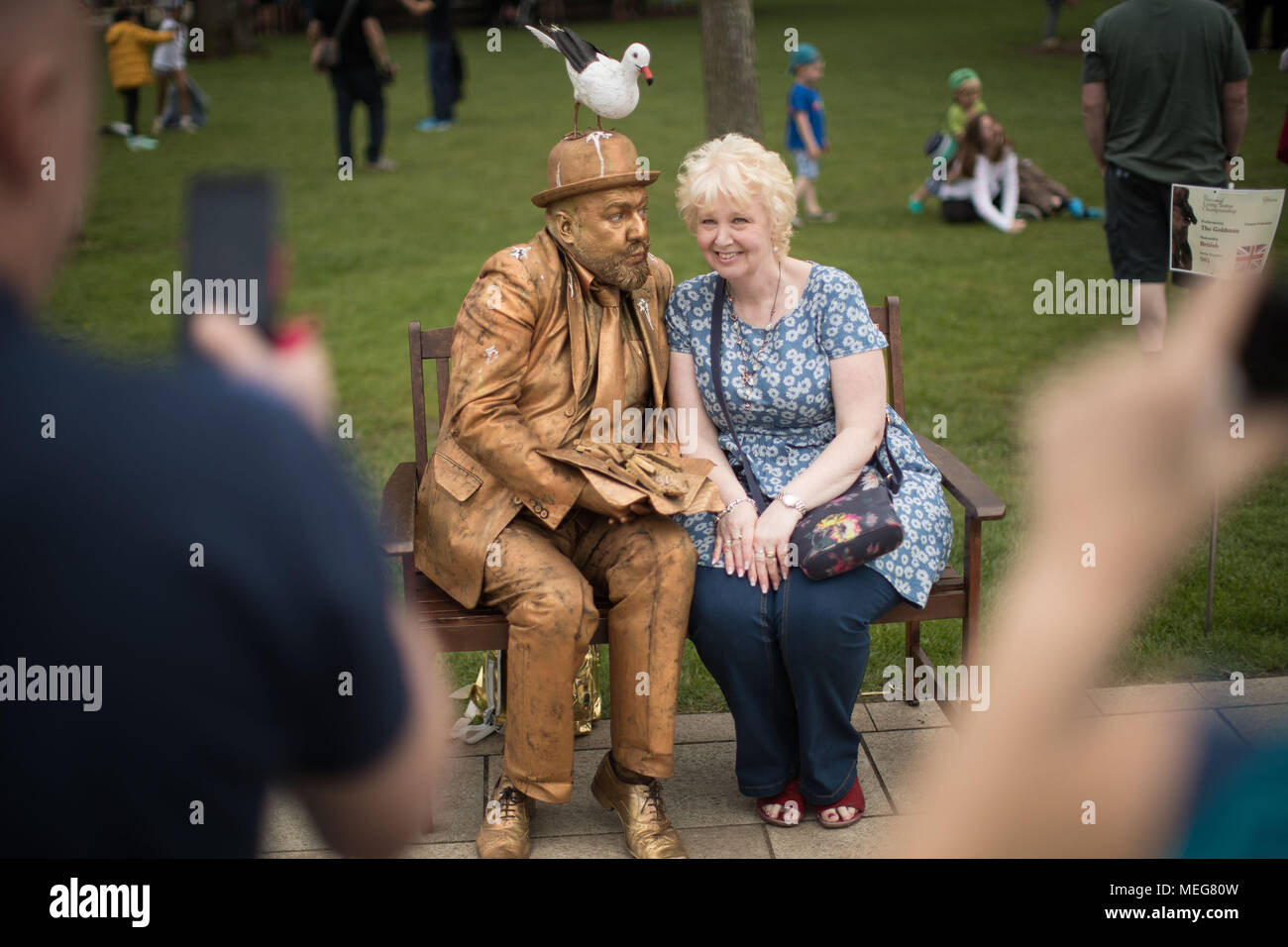 Une dame s'assoit à côté de l'artiste britannique Goldman au cours de la vie nationale statue concours pour le 454 e anniversaire de Shakespeare dans le Bancroft Garden's à Stratford-Upon-Avon. Banque D'Images