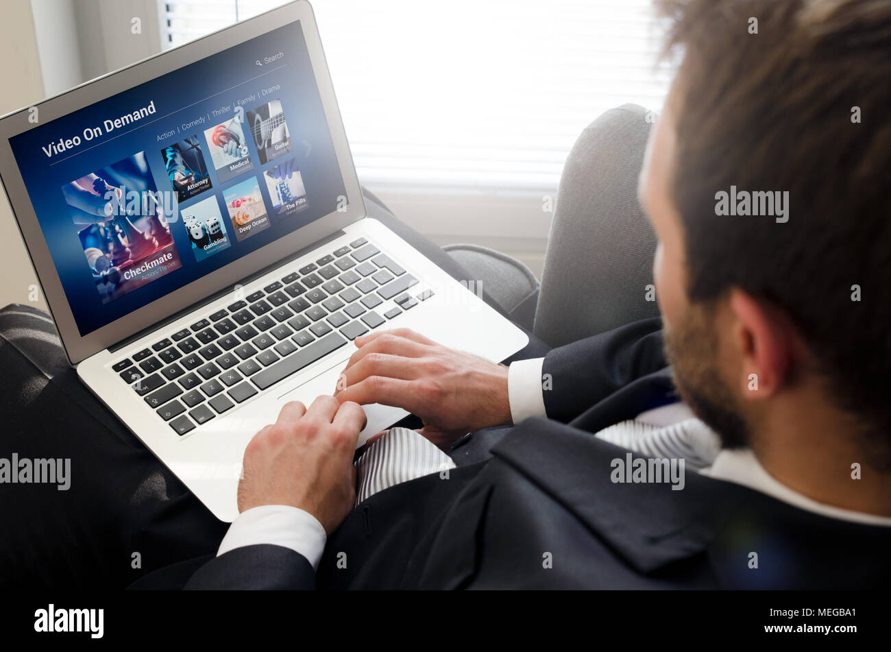 L'homme à l'aide d'ordinateur portable pour regarder la vidéo sur le service de VOD. La vidéo sur demande télévision internet stream concept multimédia Banque D'Images