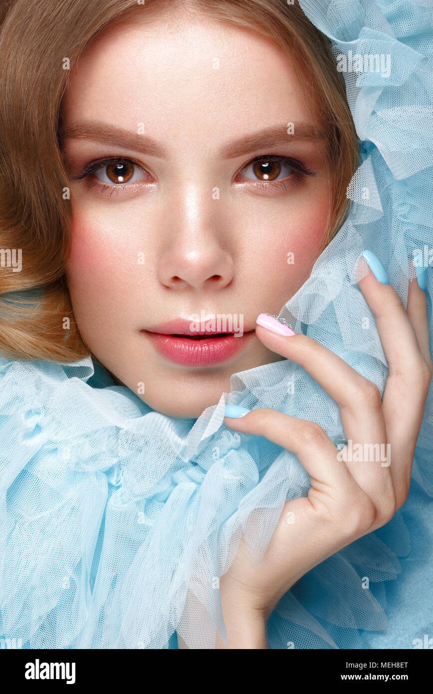 Belle fille avec la lumière douce et de maquillage manucure en bleu vêtements. Beauté Visage. Ongles Design. Banque D'Images