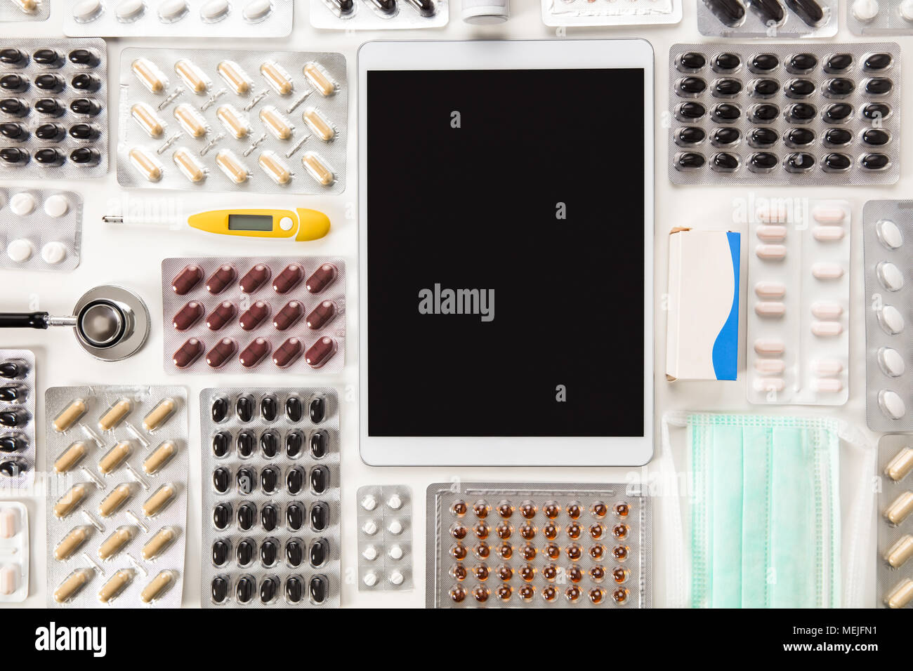 Tablette numérique entouré de pilules colorées sur la table Banque D'Images