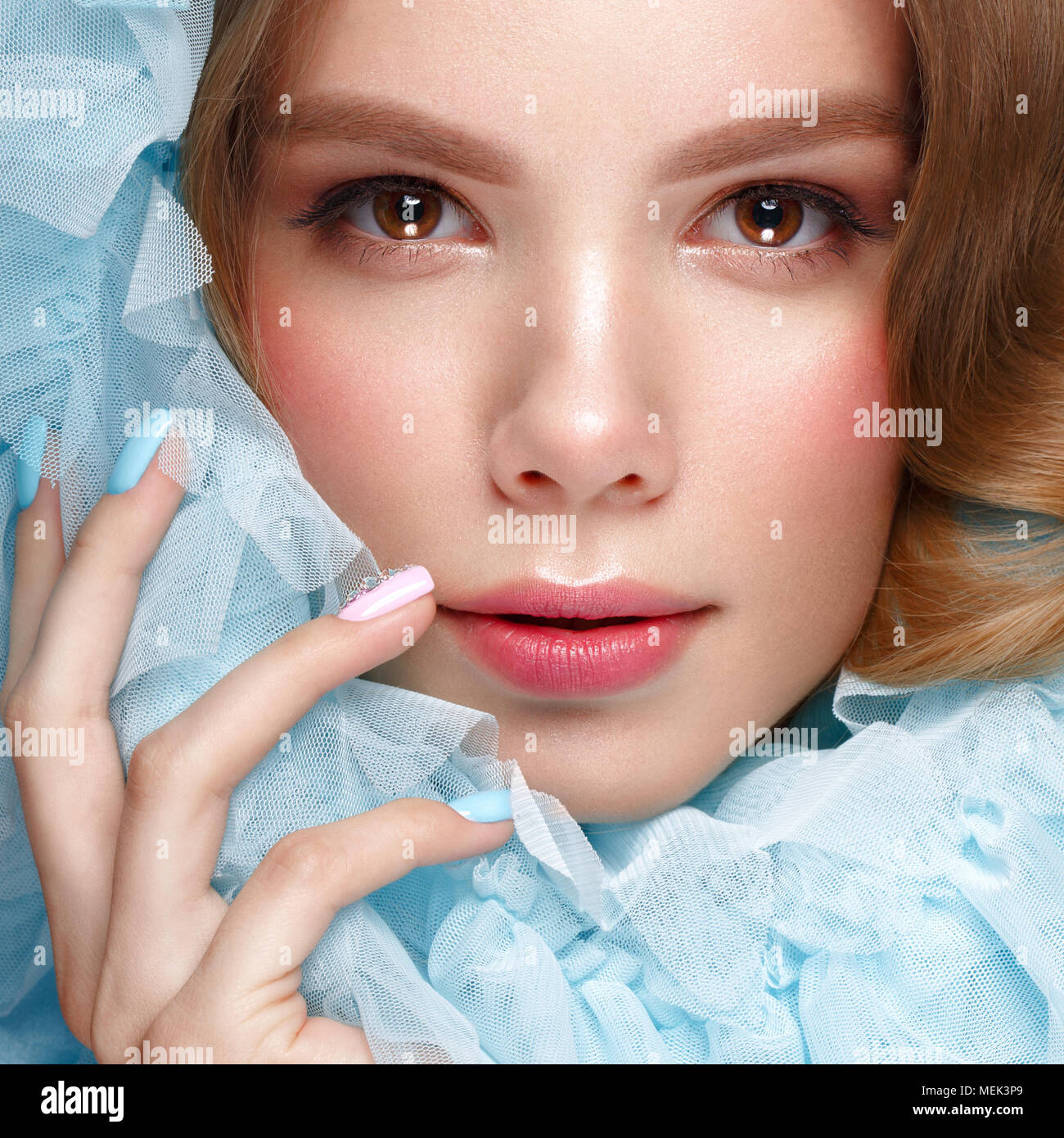 Belle fille avec la lumière douce et de maquillage manucure en bleu vêtements. Beauté Visage. Ongles Design. Banque D'Images