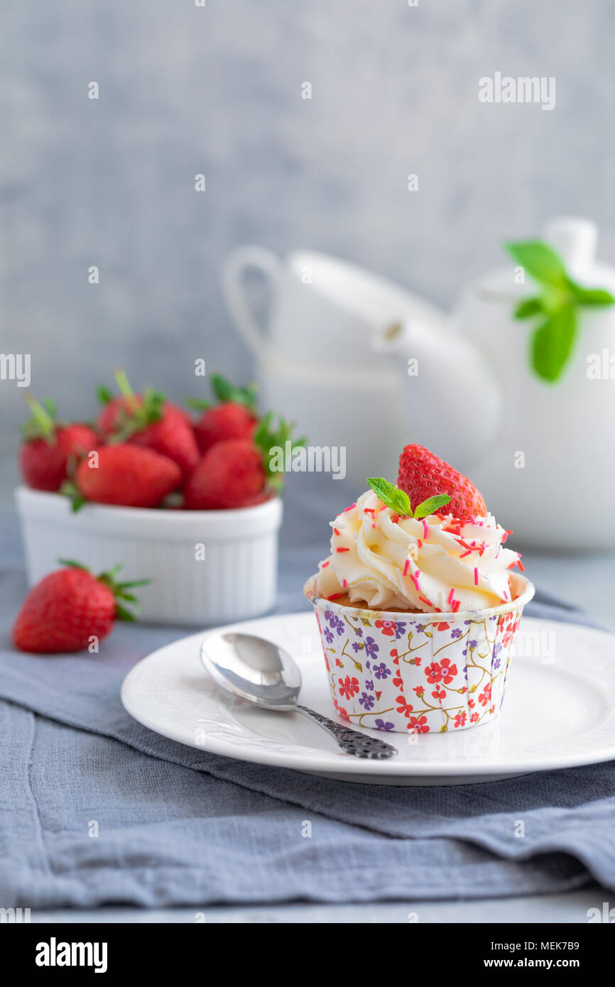 Des muffins ou cupcakes avec crème vanille et de fraises fraîches sur le fond gris clair, avec un copyspace Banque D'Images