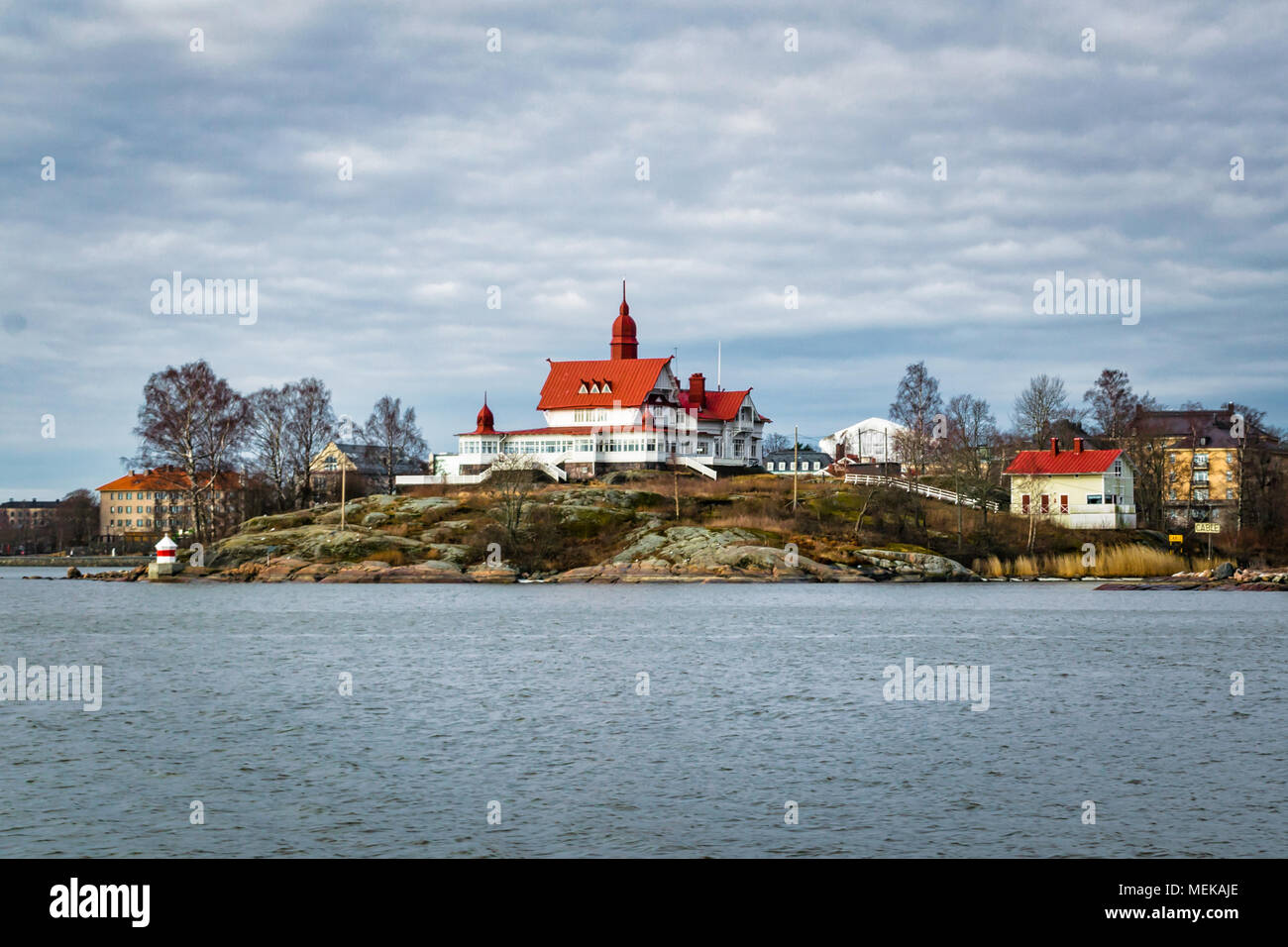 C'est Île Luoto à Helsinki, Finlande le port au début du printemps. Il y a un vieux bâtiment blanc avec un toit rouge vif Banque D'Images