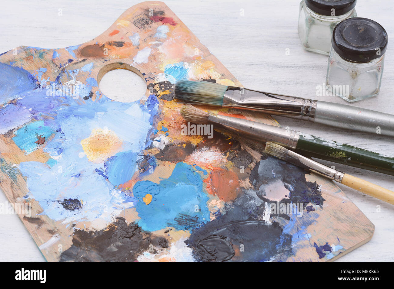 La palette de l'artiste avec des traits de peinture d'huile, pots et  pinceaux sur fond de bois blanc. Concept Art Photo Stock - Alamy