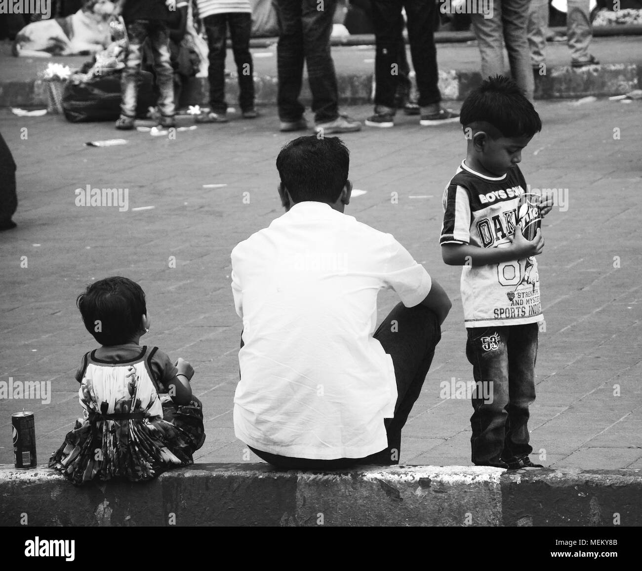 Un homme et ses enfants bénéficiant d'une pause dans les rues de Mumbai, Inde Banque D'Images