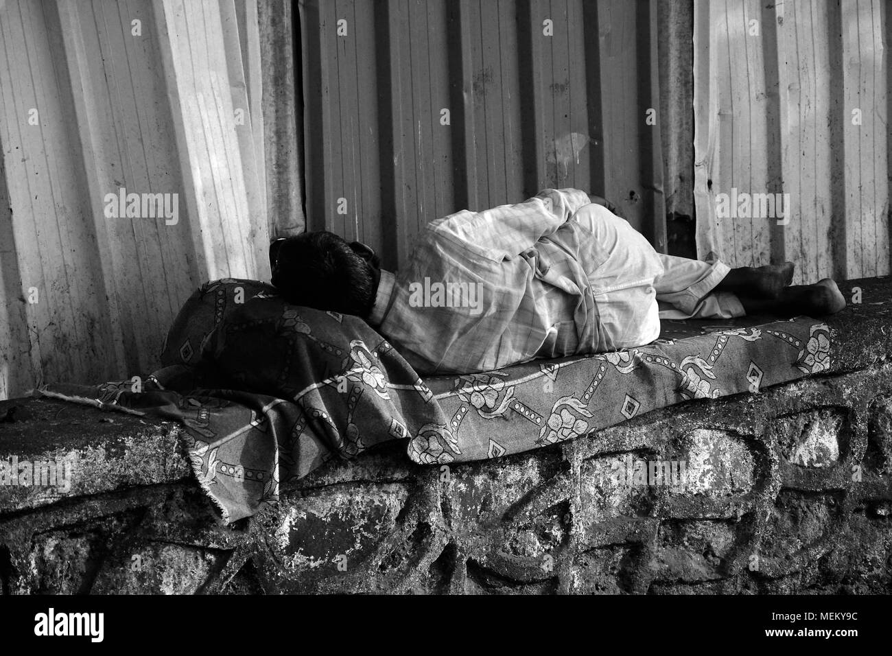 Homme endormi sur un mur dans la rue à Mumbai, Inde Banque D'Images