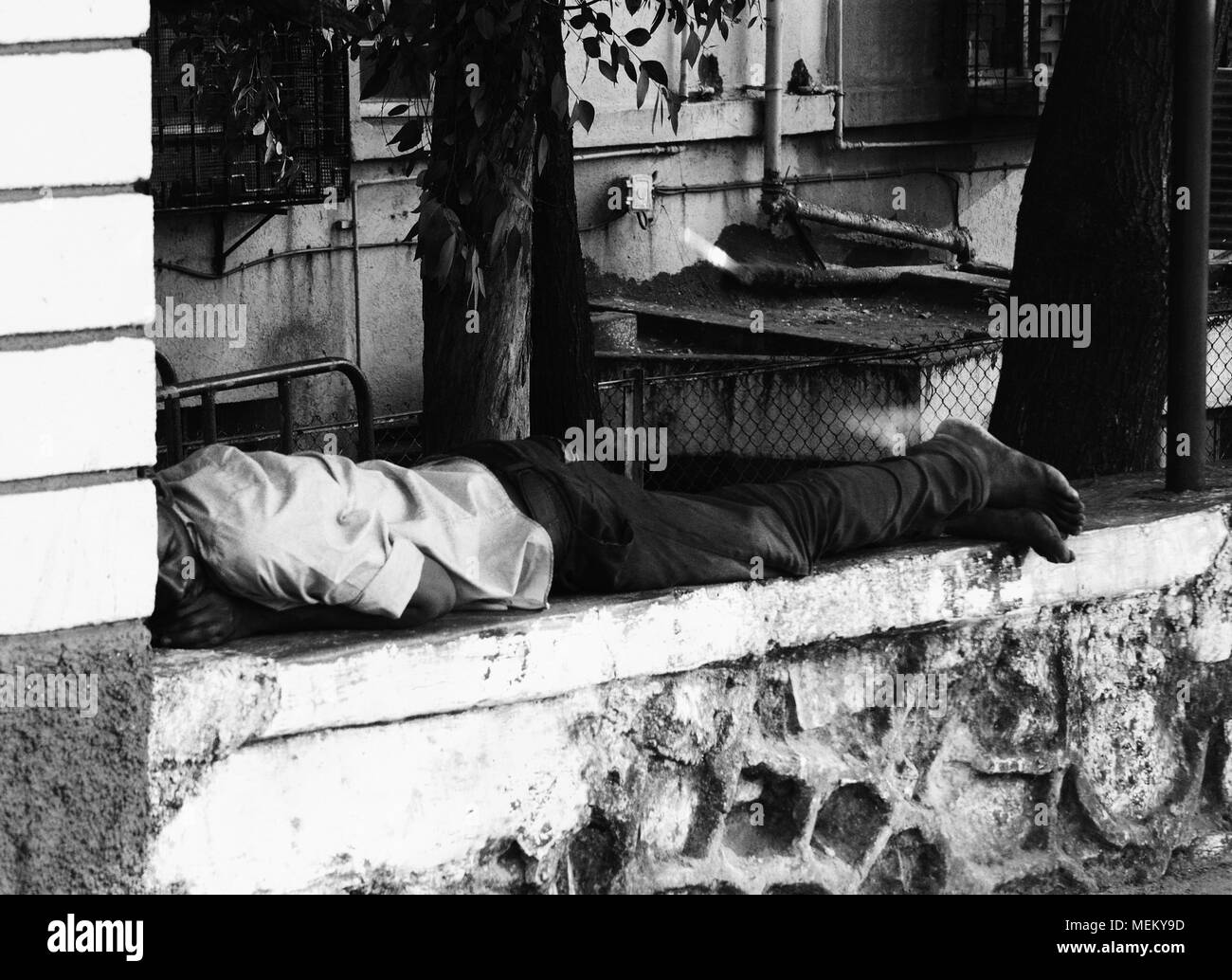 Homme endormi sur un mur dans la rue à Mumbai, Inde Banque D'Images