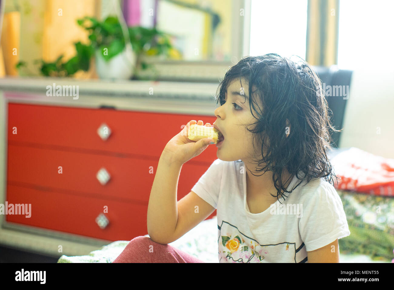 A little girl eating banana après avoir pris une douche tout en regardant la télévision Banque D'Images