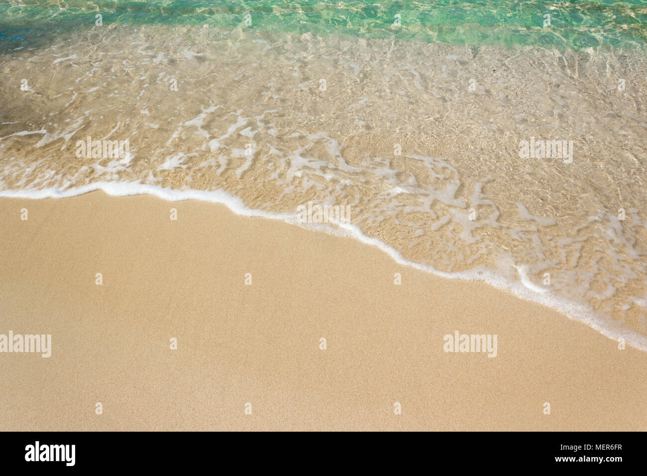 Vagues douces avec mousse de bleu océan sur la plage de sable Banque D'Images