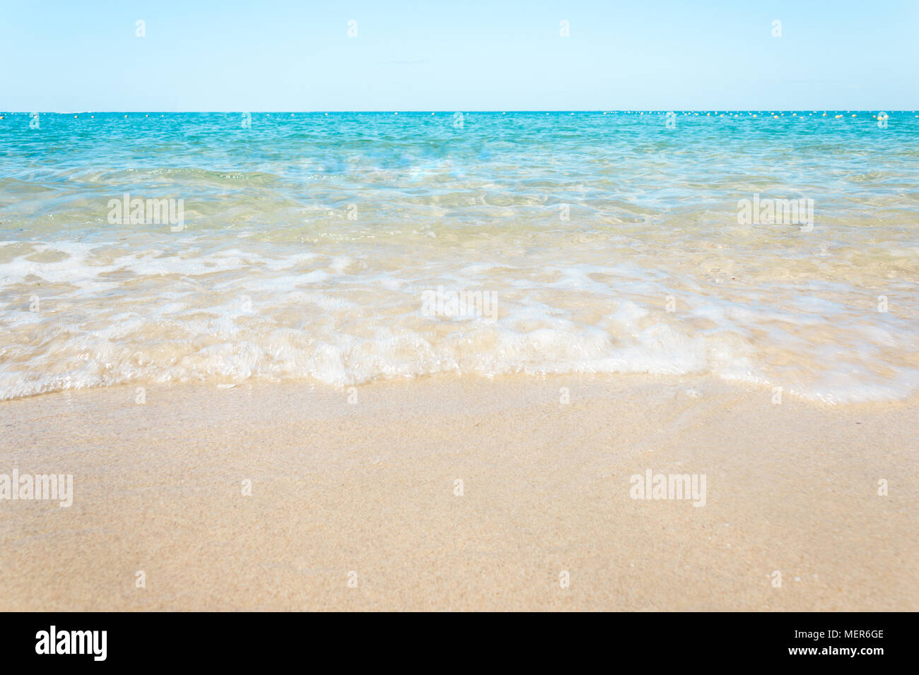 Vagues douces avec mousse de bleu océan sur la plage de sable Banque D'Images