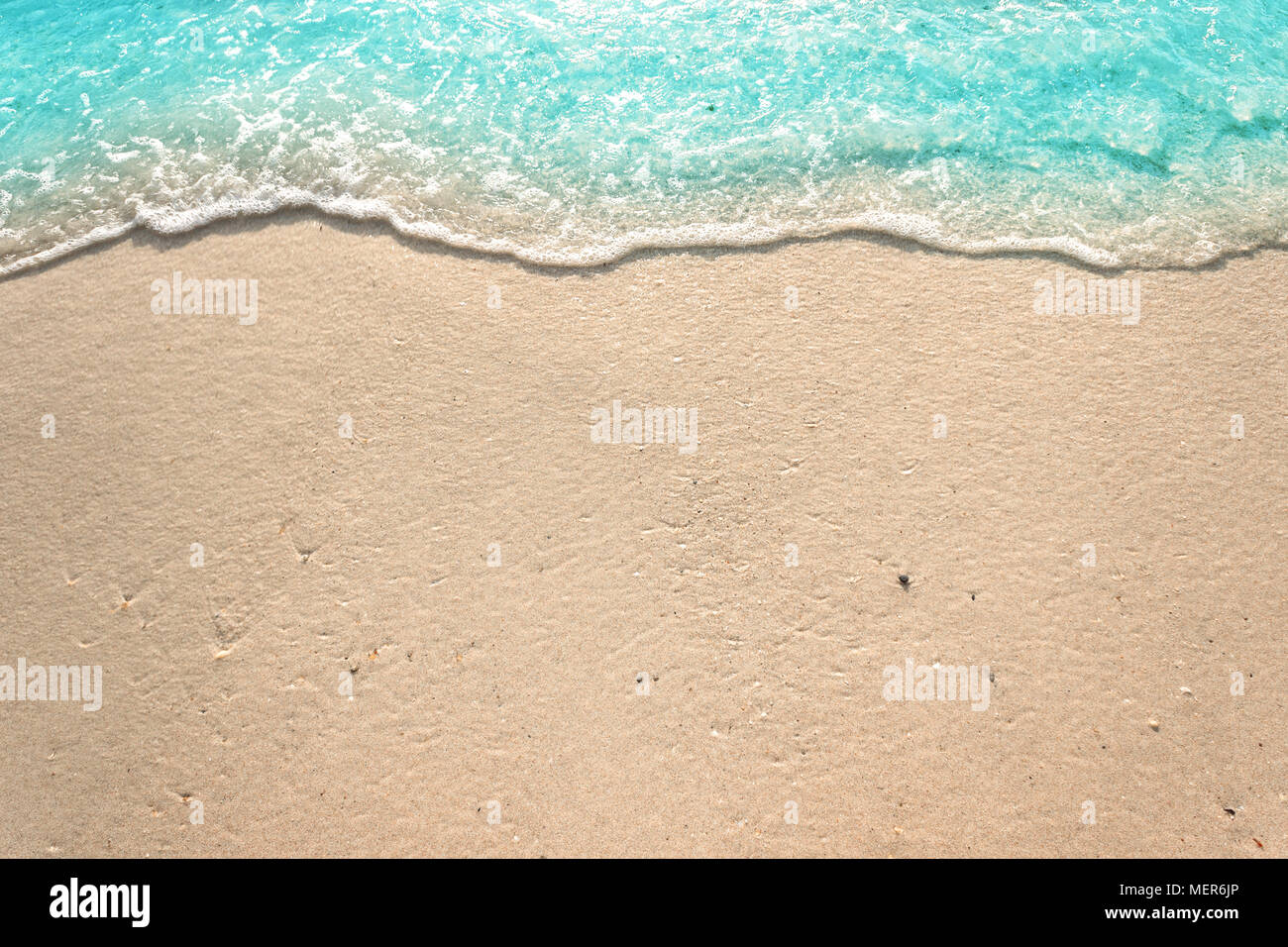 Vagues douces avec mousse de bleu océan sur la plage de sable Banque D'Images