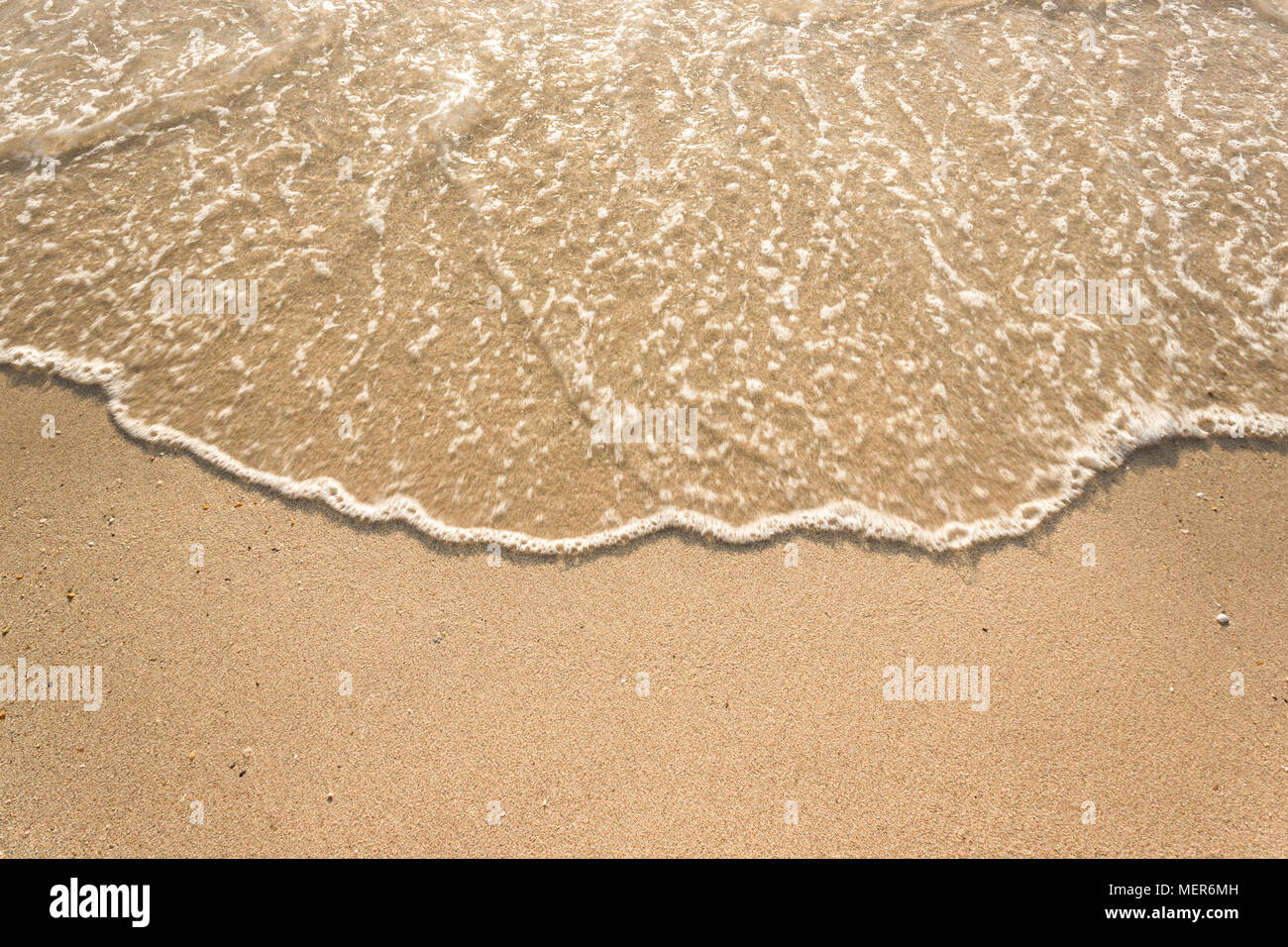 Vagues douces avec de la mousse de l'océan sur la plage de sable contexte Banque D'Images