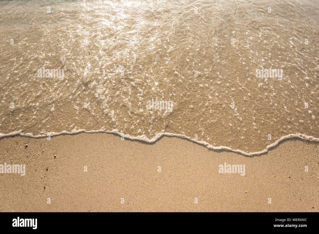 Vagues douces avec de la mousse de l'océan sur la plage de sable contexte Banque D'Images