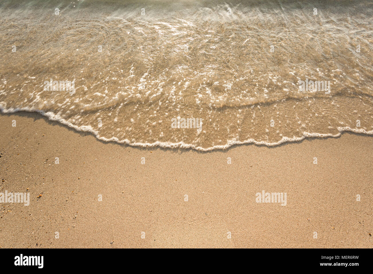 Vagues douces avec de la mousse de l'océan sur la plage de sable contexte Banque D'Images