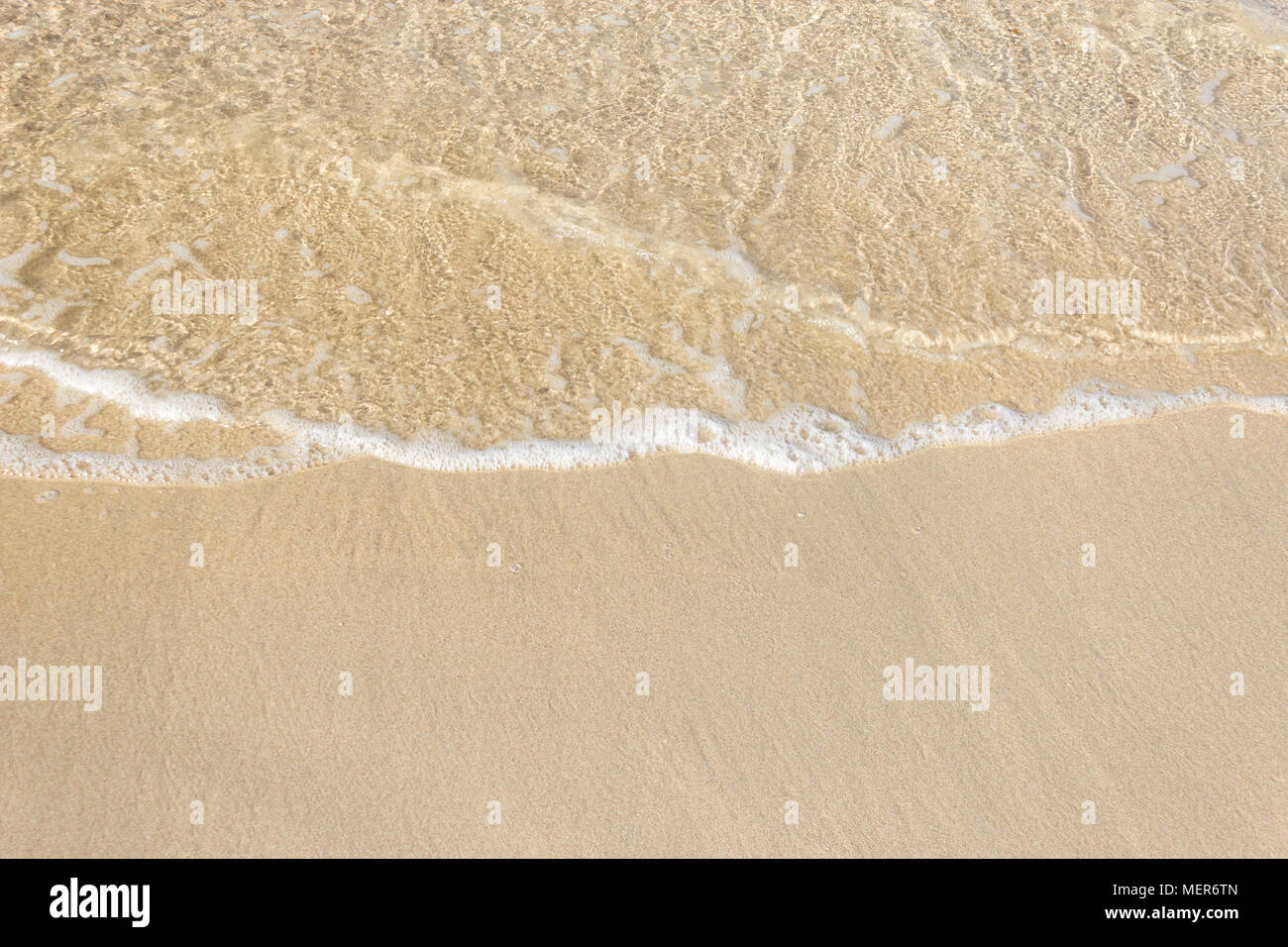 Vagues douces avec de la mousse de l'océan sur la plage de sable contexte Banque D'Images