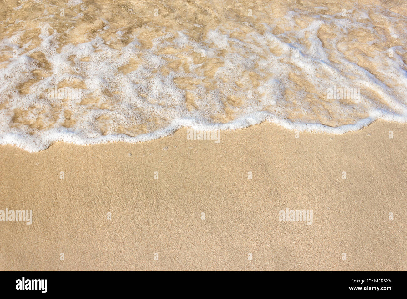 Vagues douces avec de la mousse de l'océan sur la plage de sable contexte Banque D'Images