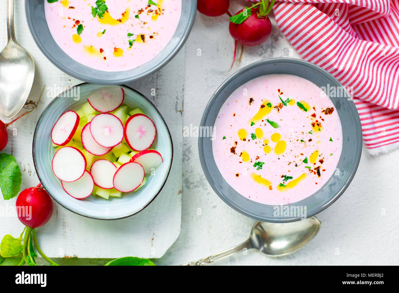 Soupe de radis froide rose avec le concombre et yaourt garnie de piment sec, le poivre, le persil, l'huile d'olive et servi dans des bols crudités Banque D'Images